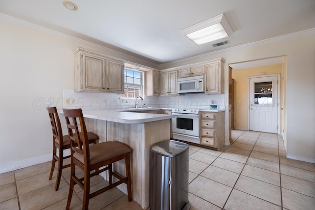 kitchen featuring decorative backsplash, white appliances, a peninsula, and light brown cabinetry