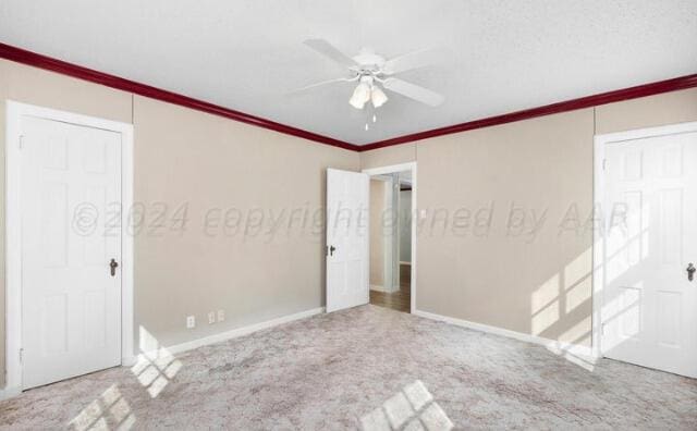 empty room with carpet flooring, crown molding, baseboards, and ceiling fan