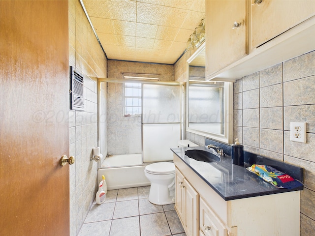 1108 Campanella Dr, Pampa, TX 79065 - bathroom with tile walls, tile patterned floors, toilet, vanity, and combined bath / shower with glass door