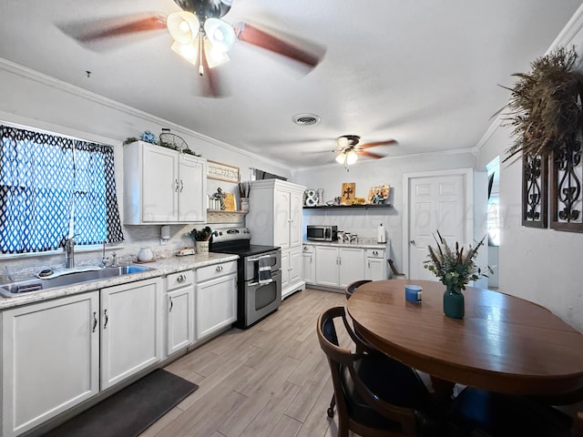 424 Santa Fe St, Borger, TX 79007 - kitchen with ceiling fan, appliances with stainless steel finishes, a sink, light wood-style floors, and white cabinets