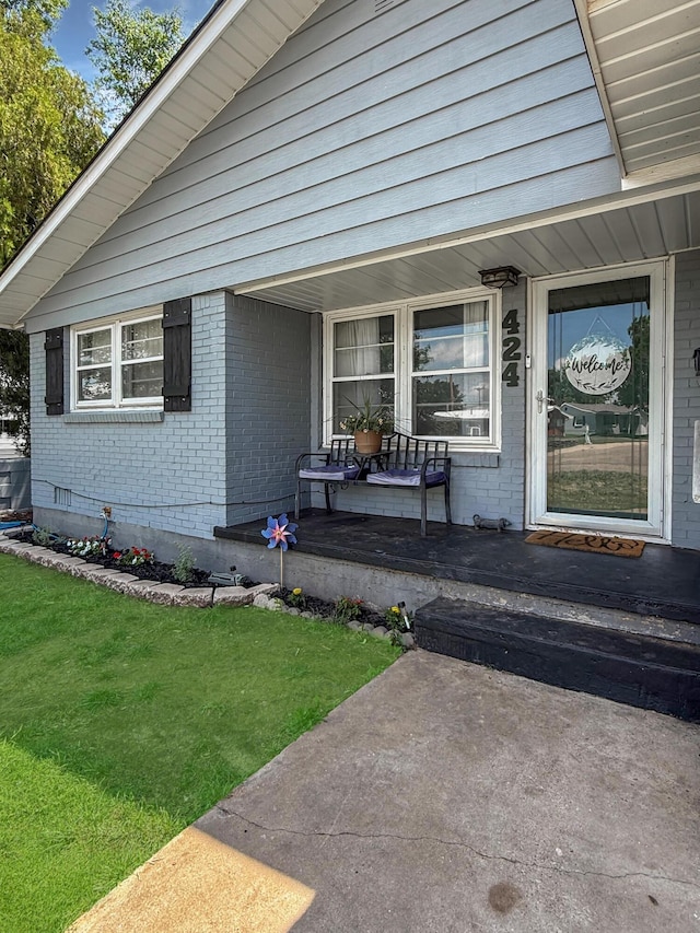 424 Santa Fe St, Borger, TX 79007 - view of exterior entry with covered porch, brick siding, and a lawn