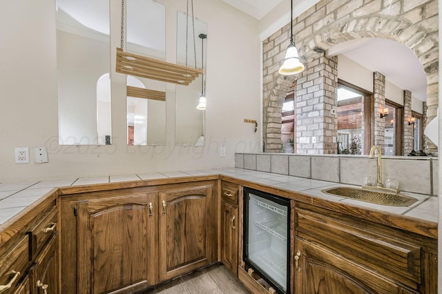 7402 Lynnlee Pl, Amarillo, TX 79121 - indoor wet bar featuring beverage cooler, ornamental molding, pendant lighting, light wood-type flooring, and tasteful backsplash