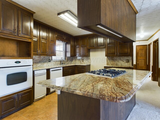 1924 N Dwight St, Pampa, TX 79065 - kitchen featuring white appliances, light stone countertops, wall chimney exhaust hood, a kitchen island, and backsplash
