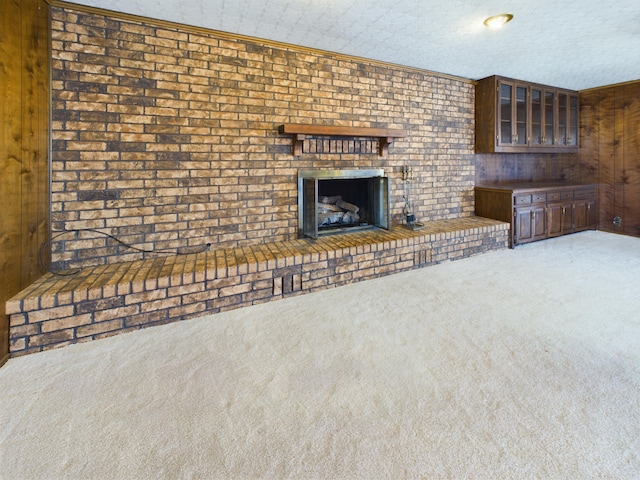 1924 N Dwight St, Pampa, TX 79065 - unfurnished living room featuring carpet flooring, a fireplace, wood walls, a textured ceiling, and ornamental molding