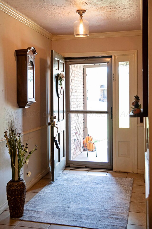 entryway with light tile patterned flooring, a textured ceiling, and ornamental molding