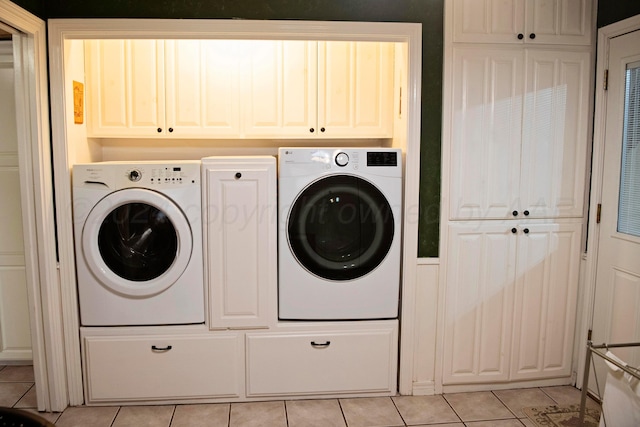 clothes washing area with cabinets, independent washer and dryer, and light tile patterned flooring