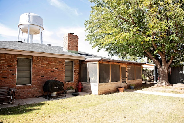 rear view of house featuring a sunroom and a yard