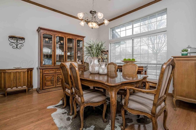 dining room featuring crown molding, light wood finished floors, and a notable chandelier