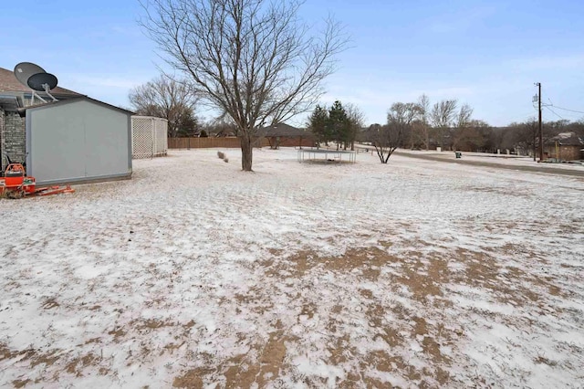 yard covered in snow with a storage shed, fence, and an outdoor structure