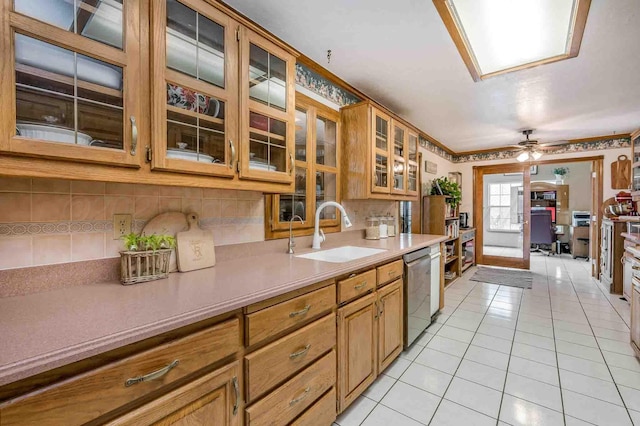 kitchen featuring glass insert cabinets, brown cabinetry, light countertops, and dishwasher