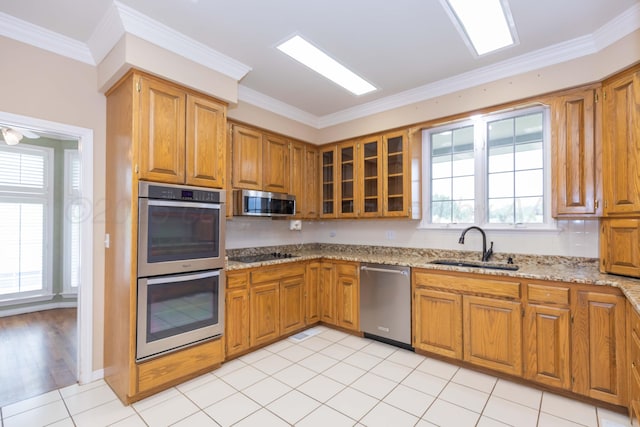 kitchen featuring a sink, brown cabinetry, stainless steel appliances, and light stone countertops