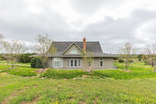 rear view of property featuring french doors, a yard, and a chimney
