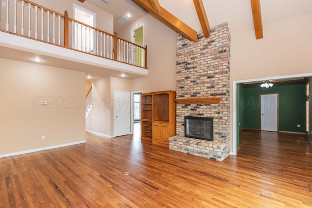 unfurnished living room with baseboards, a ceiling fan, a towering ceiling, and a fireplace