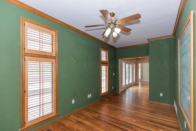 empty room with baseboards, ornamental molding, a healthy amount of sunlight, and wood finished floors