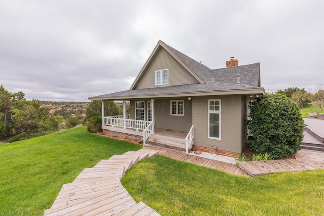 back of property with roof with shingles, a chimney, a yard, and a porch