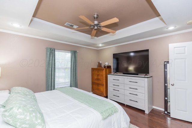 bedroom featuring ornamental molding, visible vents, a tray ceiling, and dark wood finished floors