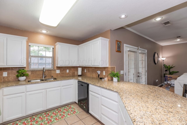 kitchen featuring white cabinets, backsplash, dishwasher, a sink, and visible vents
