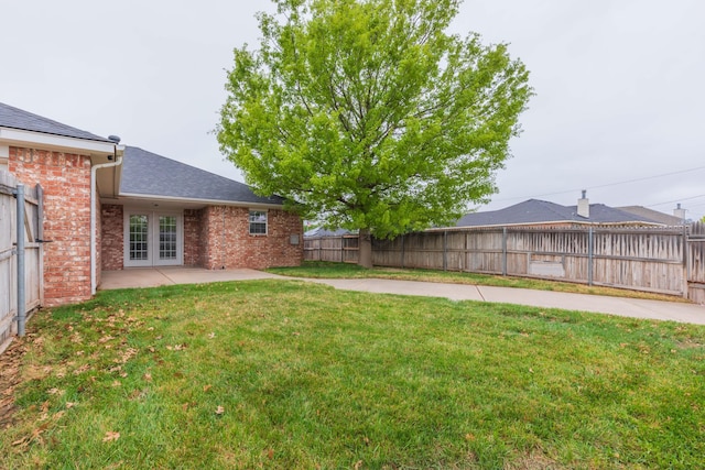 view of yard featuring french doors, a fenced backyard, and a patio area