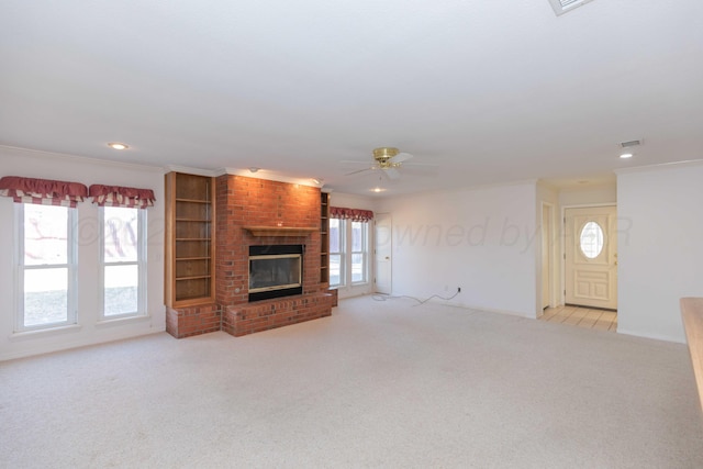 unfurnished living room featuring light carpet, a fireplace, ornamental molding, and ceiling fan