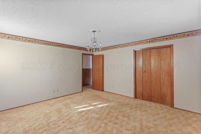 unfurnished bedroom with a closet, carpet floors, a textured ceiling, and an inviting chandelier