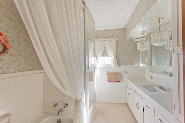 bathroom featuring vanity, a tub to relax in, a textured ceiling, and tile walls
