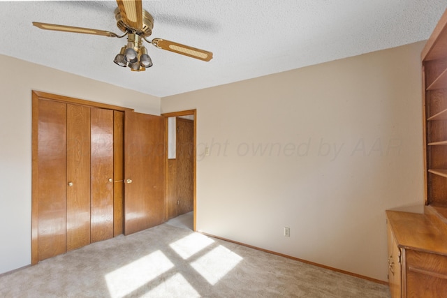 unfurnished bedroom with ceiling fan, light colored carpet, a textured ceiling, and a closet