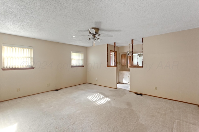 carpeted spare room featuring a textured ceiling, plenty of natural light, and ceiling fan