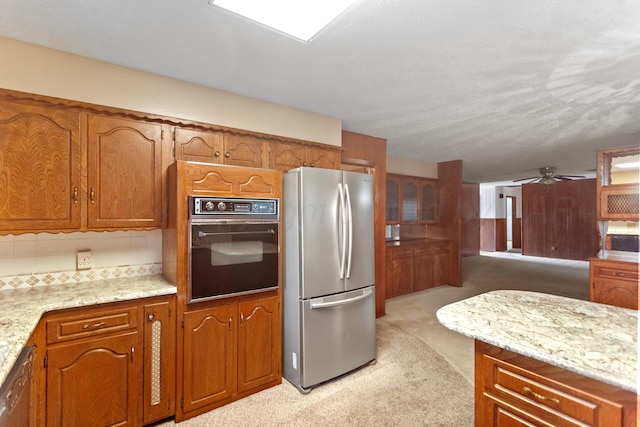 kitchen featuring light carpet, ceiling fan, a textured ceiling, light stone counters, and stainless steel appliances