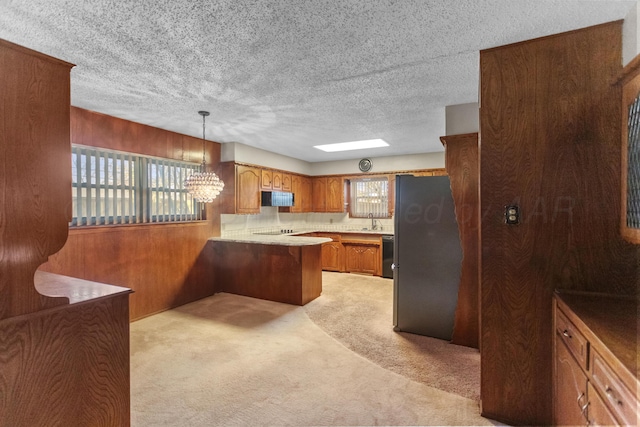 kitchen featuring light colored carpet, kitchen peninsula, hanging light fixtures, and a wealth of natural light