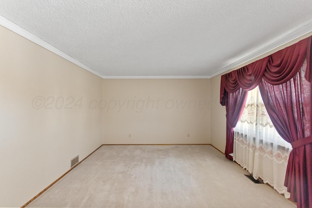 empty room with a textured ceiling, light colored carpet, and ornamental molding