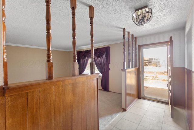 interior space with light tile patterned floors, a textured ceiling, ornamental molding, and a healthy amount of sunlight
