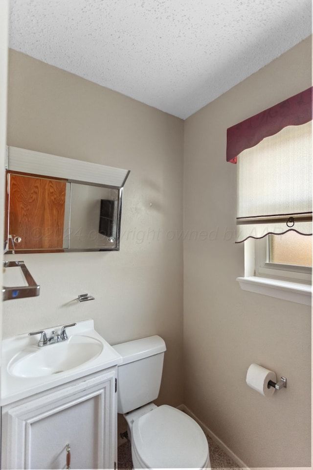 bathroom with vanity, toilet, and a textured ceiling