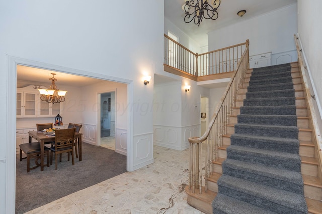 stairs featuring a notable chandelier, a towering ceiling, and carpet floors