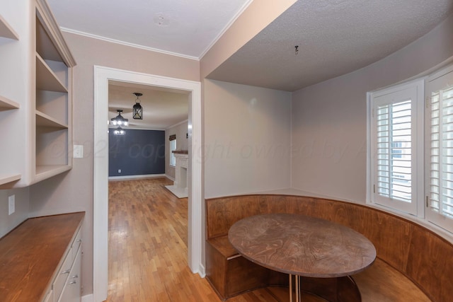 dining room featuring a textured ceiling, light wood-type flooring, and ornamental molding