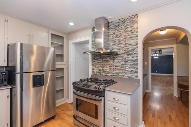 kitchen featuring wall chimney exhaust hood, white cabinetry, appliances with stainless steel finishes, and tasteful backsplash