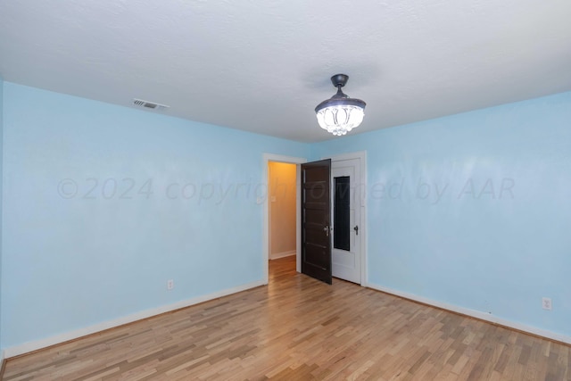 unfurnished room featuring light hardwood / wood-style floors and a chandelier