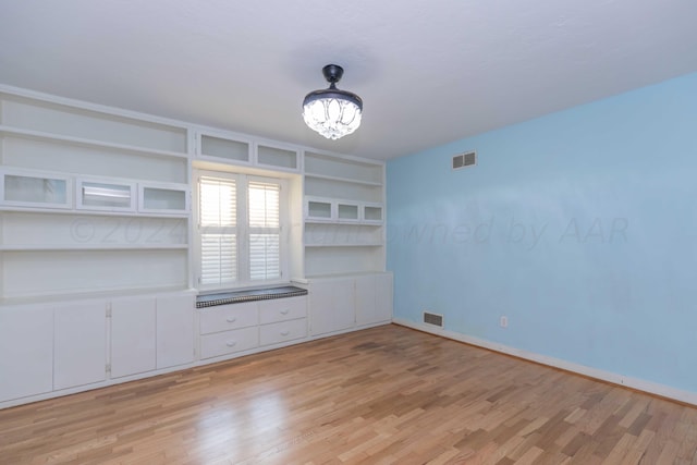 unfurnished living room with a chandelier, light hardwood / wood-style floors, and built in features