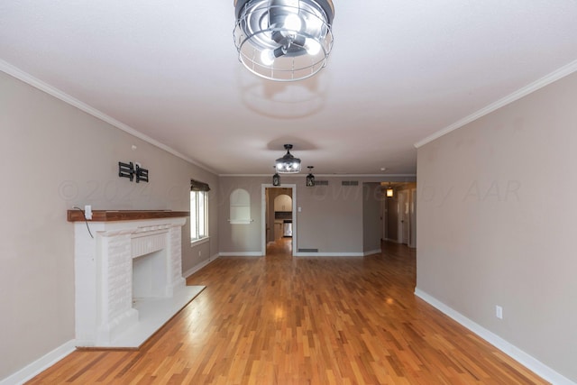 unfurnished living room featuring crown molding, wood-type flooring, and a brick fireplace