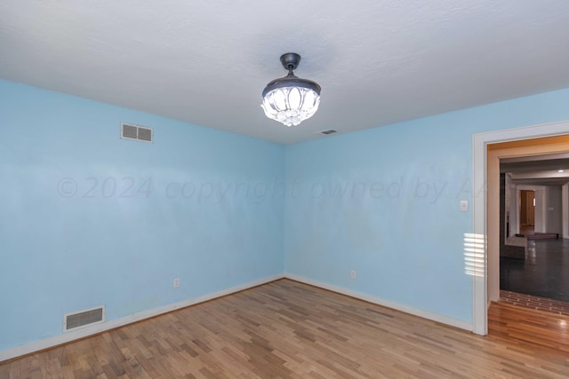 spare room featuring hardwood / wood-style floors and an inviting chandelier