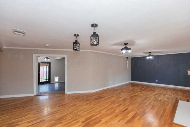 unfurnished room with a textured ceiling, hardwood / wood-style flooring, and ornamental molding