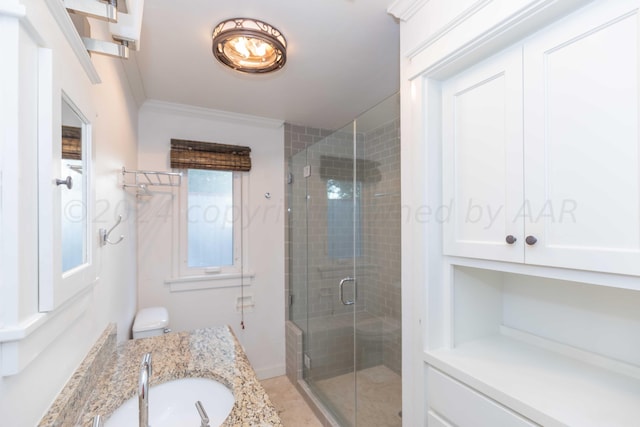 bathroom with vanity, a shower with shower door, and ornamental molding