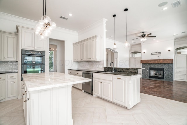 kitchen featuring stainless steel dishwasher, a sink, dobule oven black, visible vents, and ceiling fan with notable chandelier