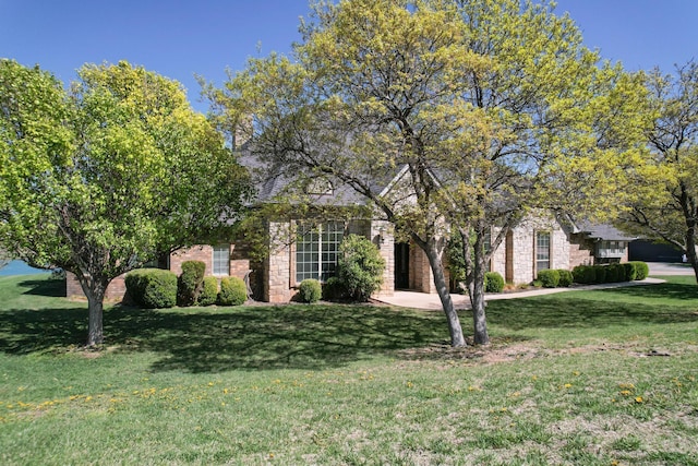 obstructed view of property with brick siding and a front lawn