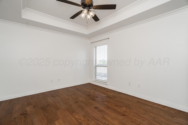 spare room featuring crown molding, a tray ceiling, and dark wood finished floors