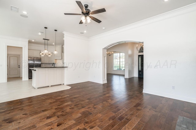 unfurnished living room with wood finished floors, visible vents, crown molding, baseboards, and ceiling fan with notable chandelier