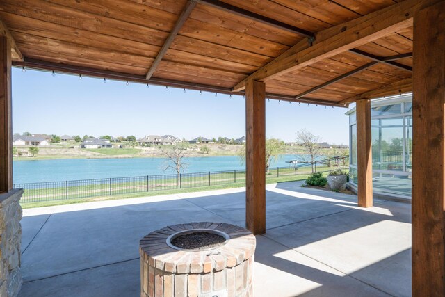 view of patio featuring fence, a fire pit, and a water view
