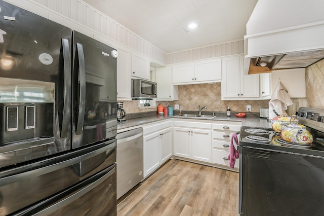 kitchen featuring black appliances, sink, custom range hood, white cabinetry, and light wood-type flooring