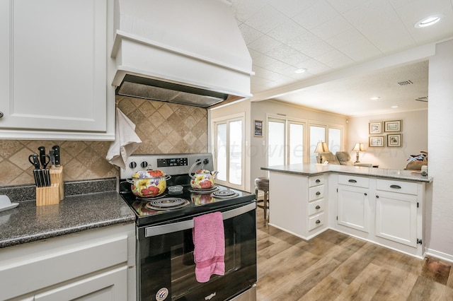 kitchen with white cabinetry, kitchen peninsula, light wood-type flooring, stainless steel electric range, and premium range hood