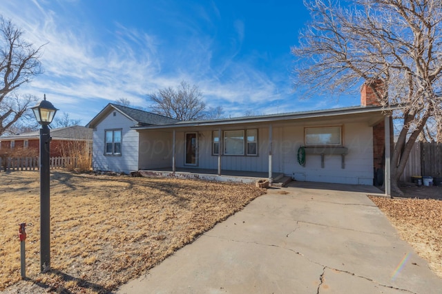 ranch-style house with a porch, a chimney, and fence