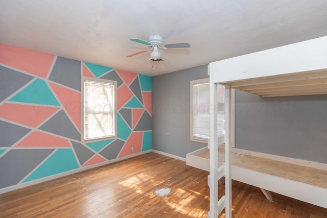 unfurnished bedroom featuring a ceiling fan, hardwood / wood-style flooring, and baseboards